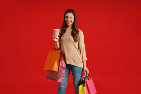 Beautiful young woman in casual clothing carrying shopping bags and winkingの写真素材