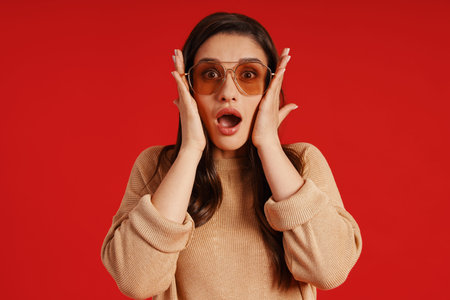 Shocked young woman in casual clothing making a face and looking at camera