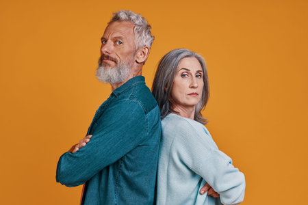 Beautiful senior couple keeping arms crossed and looking at camera