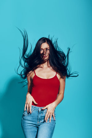 Attractive young woman looking at camera and smiling while standing against blue background