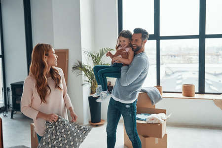 Playful young family smiling and unboxing their stuff while moving into a new apartmentの写真素材