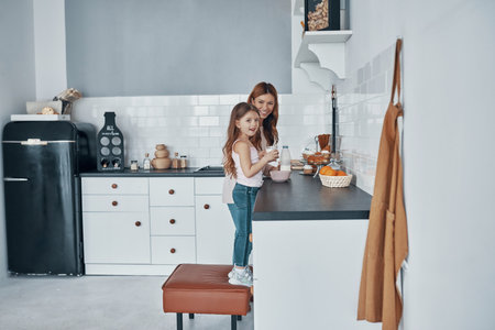Mother and daughter smiling while preparing something at the kitchenの写真素材