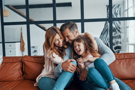 Happy young family with girl preschool age smiling while bonding togetherの写真素材