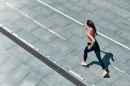 Top view of attractive young woman in sports clothing running outdoors