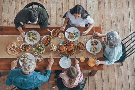 Top view of multi-generation family communicating and smiling while having dinner togetherの写真素材