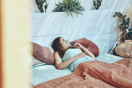 Beautiful young woman smiling while waking up in the morningの写真素材