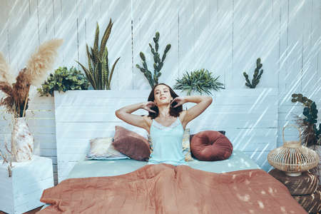 Beautiful young woman stretching while waking up in the morningの写真素材