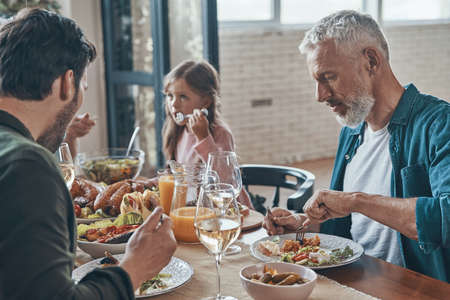 Happy multi-generation family communicating and smiling while having dinner togetherの写真素材