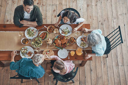 Top view of multi-generation family communicating and smiling while having dinner togetherの写真素材