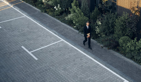 Top view of mature man in full suit carrying laptop while walking outdoorsの写真素材