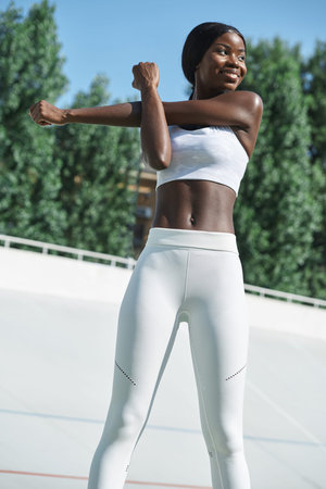 Confident young African woman in sports clothing exercising outdoors