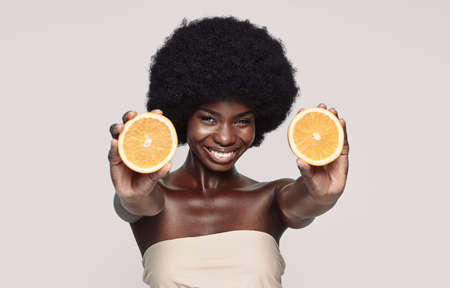 Portrait of beautiful young African woman holding orange pieces and smilingの写真素材
