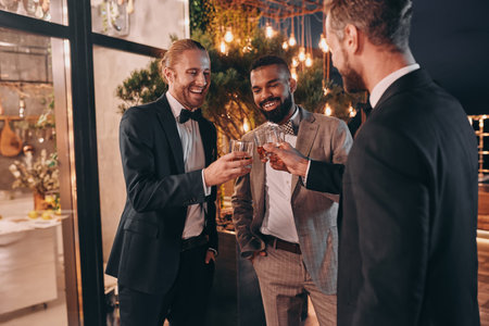 Three well-dressed men drinking whiskey and communicating while spending time on party