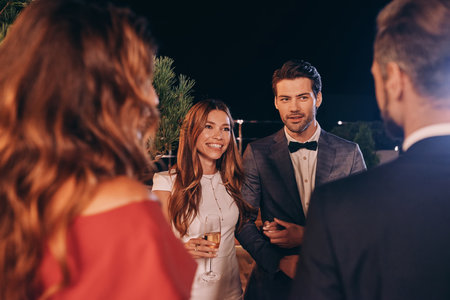 Group of people in formalwear communicating and smiling while spending time on luxury partyの写真素材