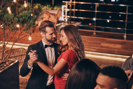 Beautiful young people dancing and smiling while spending time on luxury partyの写真素材