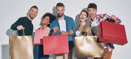 Group of young beautiful people in casual clothing carrying shopping bags and smilingの写真素材