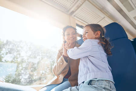 Happy mother with little daughter having fun while traveling by train togetherの写真素材