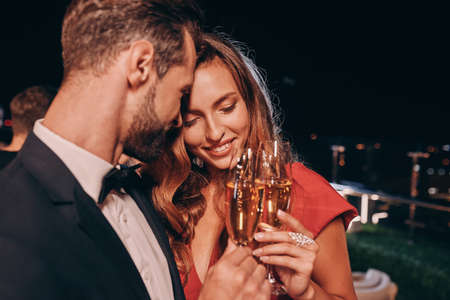 Beautiful young couple in formalwear toasting with champagne and smilingの写真素材