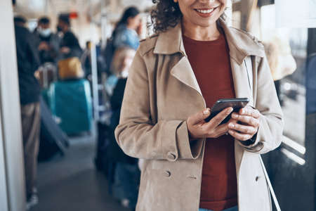 Close-up of beautiful mature woman using smart phone and smiling while traveling by trainの写真素材