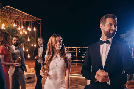 Beautiful young couple in formalwear spending time on luxury party with friendsの写真素材