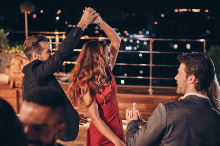 Beautiful young people dancing and smiling while spending time on luxury party