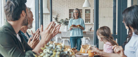 Happy multi-generation family communicating and smiling while having dinner togetherの写真素材