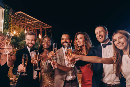 Group of people in formalwear toasting with champagne and smiling while spending time on luxury partyの写真素材