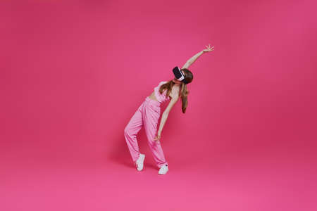 Full length of playful young woman in virtual reality headset having funの写真素材