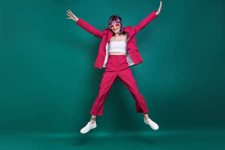 Hipster young woman jumping against green backgroundの写真素材