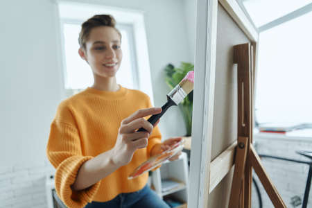 Beautiful young woman looking inspired while drawing in art studioの写真素材