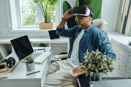 Confident African man wearing virtual reality glasses while sitting at the desk
