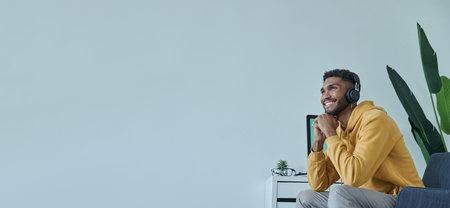 Dreamful African man holding digital tablet and smiling while sitting at his working place