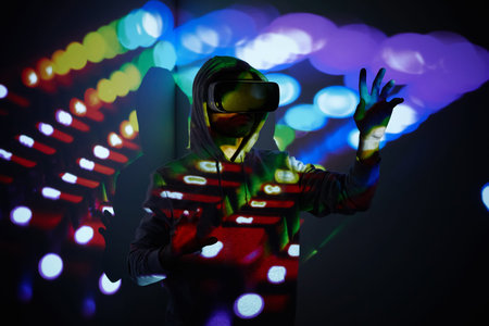 Young man wearing virtual reality glasses and gesturing against multi colored background