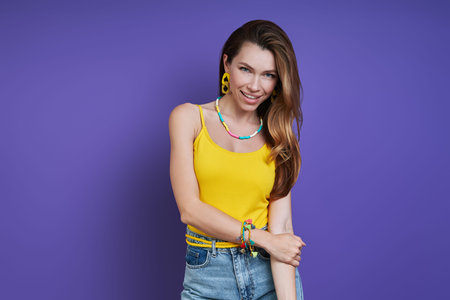 Beautiful young woman smiling while standing against purple background