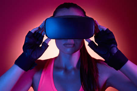 Young woman wearing virtual reality glasses against colorful backgroundの写真素材