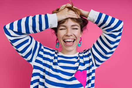 Beautiful young woman adjusting hair and smiling while standing against colored background