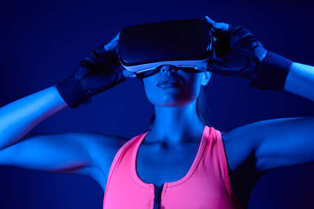 Confident young woman in sports clothing wearing virtual reality glassesの写真素材
