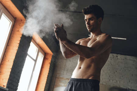Concentrated young man preparing hands with talcum powder before trainingの写真素材