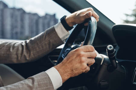 Close-up of man holding hands on steering wheel while driving a carの写真素材
