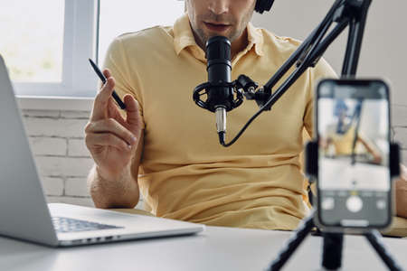 Close-up of unrecognizable man using microphone while recording podcast in studioの写真素材