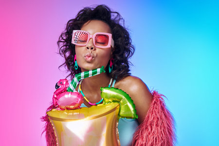 Playful African woman holding funky balloon against colorful backgroundの写真素材