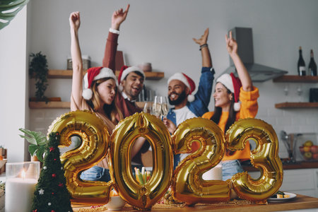 Happy young people celebrating New Year with gold colored decoration on foreground
