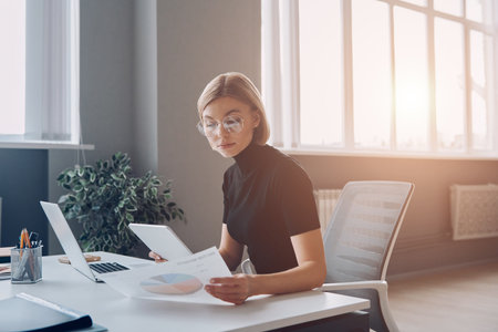 Confident young businesswoman analyzing data while working in the officeの写真素材