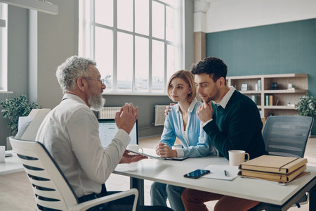 Financial advisor having meeting with his clients while sitting in the office togetherの写真素材
