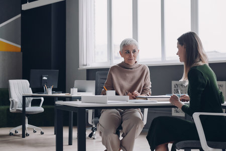 Woman having interview with confident HR manager while sitting at the office desk togetherの写真素材