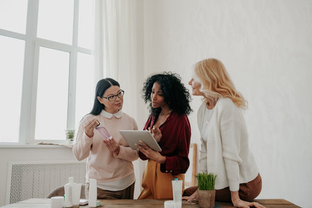 Three mature women buying beauty products online while spending time togetherの写真素材