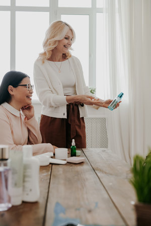 Two confident mature women smiling while examining beauty products togetherの写真素材