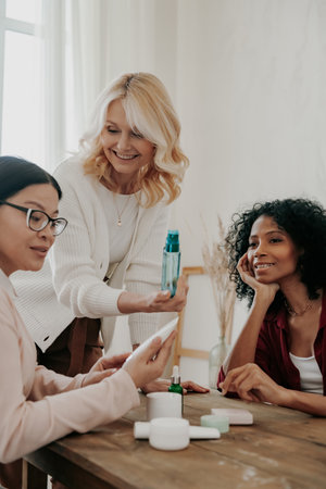 Confident mature woman advising beauty products to friends while spending time togetherの写真素材