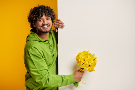 Handsome Indian man holding bouquet of flowers against colorful backgroundの写真素材