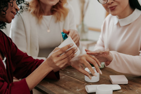 Close-up of mature women testing beauty products while sitting at the desk togetherの写真素材